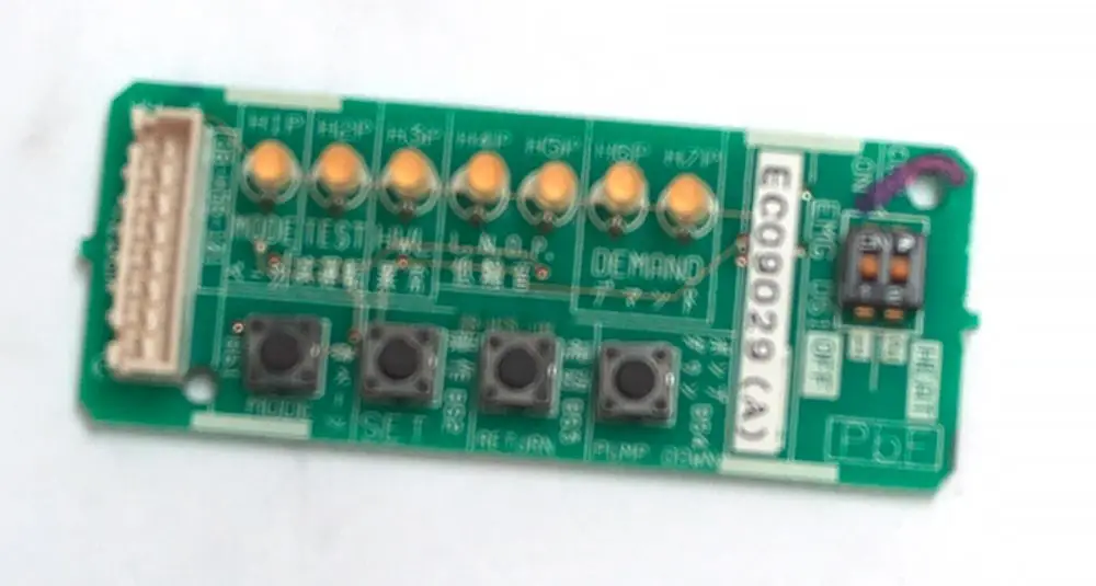 Grüne Platine mit mehreren Tasten, LEDs und einem Anschlussstecker, vermutlich von Daikin, möglicherweise für Steuerungs- oder Anzeigezwecke.